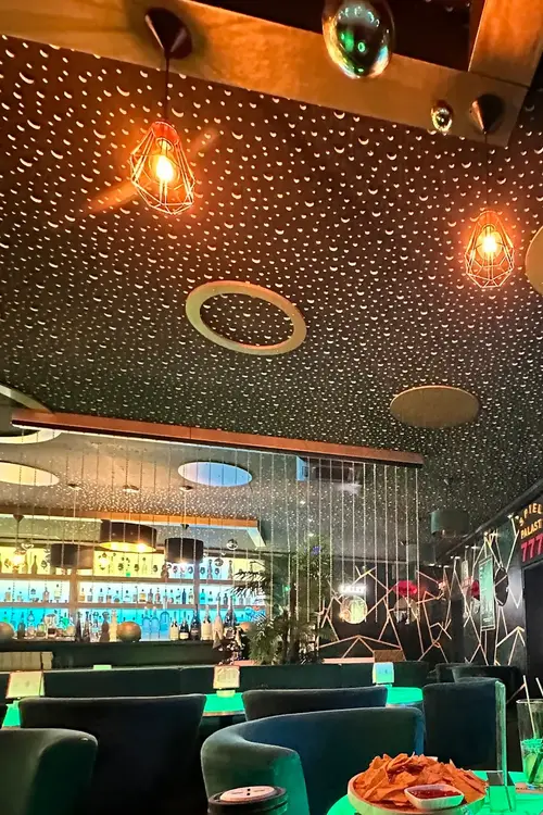 Sternenhimmel-Decke mit Kupferlampen, dahinter die Bar
