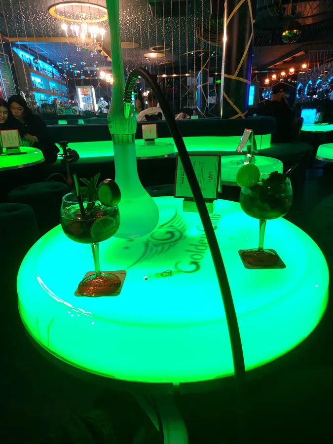 Shisha und zwei Cocktails auf einem leuchtenden Tisch mit Golden-Club-Logo